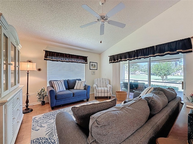 living area featuring a textured ceiling, ceiling fan, light wood-style floors, baseboards, and high vaulted ceiling