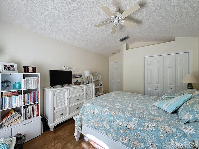 bedroom featuring dark wood-style flooring, vaulted ceiling, a textured ceiling, a closet, and ceiling fan