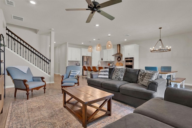 living area with recessed lighting, ceiling fan, a chandelier, stairway, and baseboards