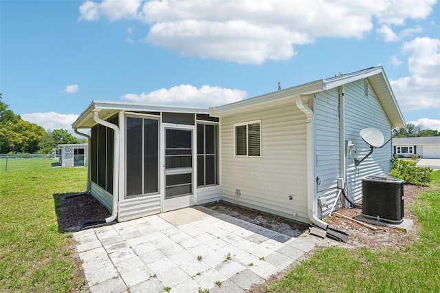11214 SW 77th Ct, Ocala, FL 34476 - rear view of property featuring a sunroom, a patio, central air condition unit, and a lawn