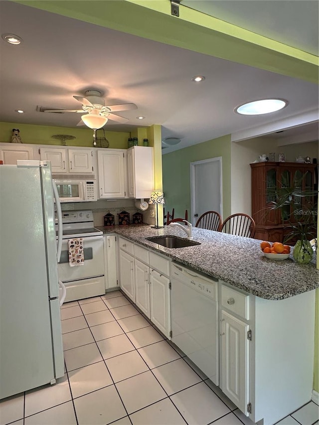 kitchen featuring white appliances, a sink, a peninsula, white cabinets, and recessed lighting