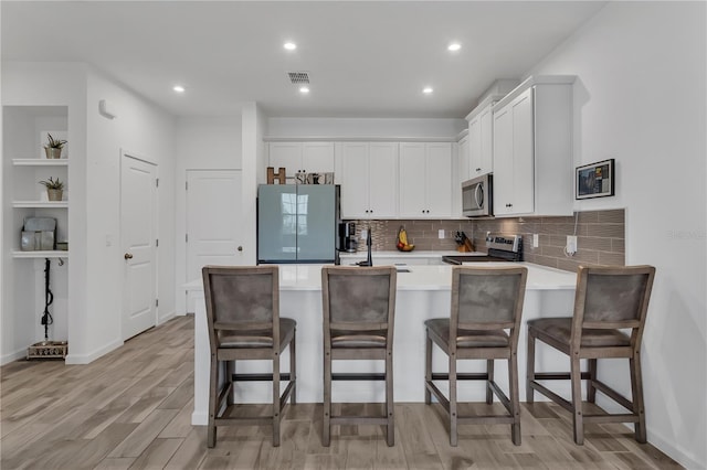 2552 Chickasaw Plum Loop, Clermont, FL 34711 - kitchen featuring stainless steel appliances, a peninsula, light wood-style flooring, white cabinets, and light countertops