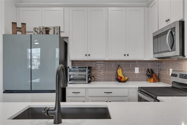 2552 Chickasaw Plum Loop, Clermont, FL 34711 - kitchen featuring appliances with stainless steel finishes, decorative backsplash, white cabinetry, and a sink