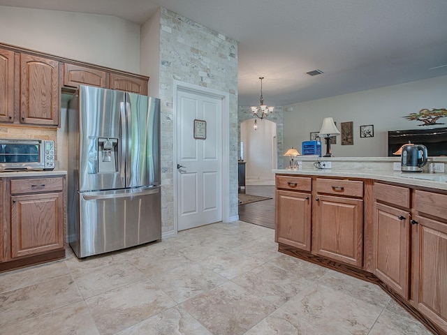 3136 Vandenberg Ct, The Villages, FL 32163 - kitchen with stainless steel refrigerator with ice dispenser, a chandelier, brown cabinets, and hanging light fixtures