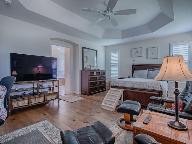3136 Vandenberg Ct, The Villages, FL 32163 - bedroom with a raised ceiling, arched walkways, wood finished floors, baseboards, and ceiling fan