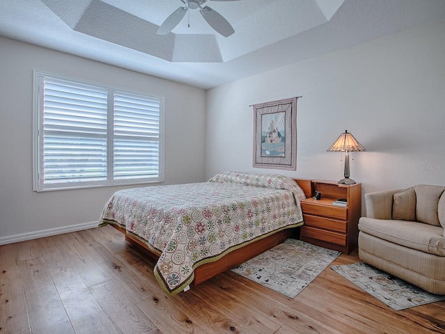 3136 Vandenberg Ct, The Villages, FL 32163 - bedroom featuring wood finished floors, baseboards, a tray ceiling, and a ceiling fan