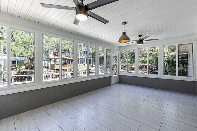 unfurnished sunroom featuring ceiling fan and plenty of natural light