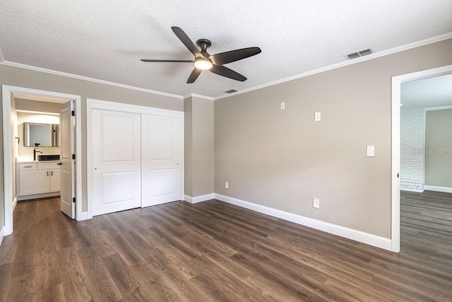 unfurnished bedroom with dark wood finished floors, baseboards, a textured ceiling, a closet, and connected bathroom