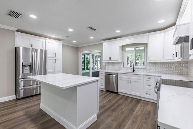 kitchen with stainless steel appliances, crown molding, dark wood-type flooring, tasteful backsplash, and white cabinetry