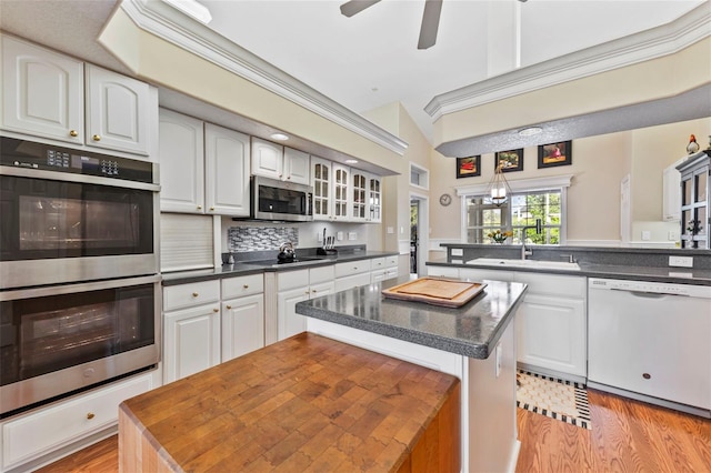 34021 Park Ln, Leesburg, FL 34788 - kitchen featuring stainless steel appliances, a kitchen island, dark countertops, and light wood finished floors