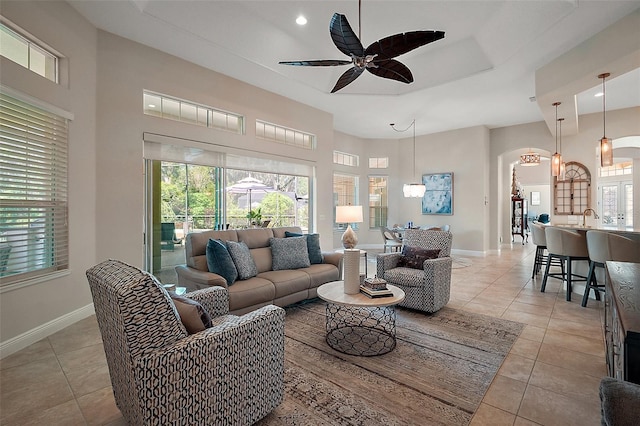 2204 Baypoint Way, The Villages, FL 32162 - living room featuring arched walkways, a high ceiling, a ceiling fan, light tile patterned flooring, and baseboards