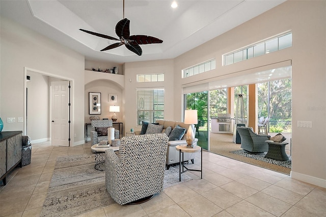 2204 Baypoint Way, The Villages, FL 32162 - living room featuring light tile patterned floors, ceiling fan, a tray ceiling, a high ceiling, and baseboards