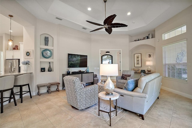 2204 Baypoint Way, The Villages, FL 32162 - living area featuring light tile patterned floors, a ceiling fan, built in features, a tray ceiling, and a high ceiling