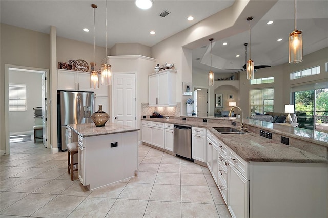 2204 Baypoint Way, The Villages, FL 32162 - kitchen featuring a sink, appliances with stainless steel finishes, a kitchen island, tasteful backsplash, and a peninsula