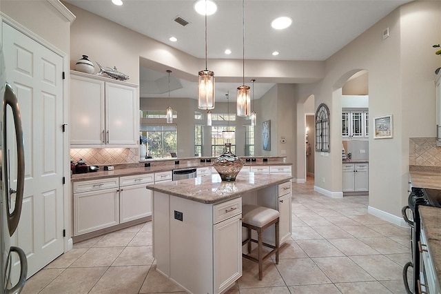 2204 Baypoint Way, The Villages, FL 32162 - kitchen with stainless steel appliances, arched walkways, tasteful backsplash, a kitchen breakfast bar, and light tile patterned flooring