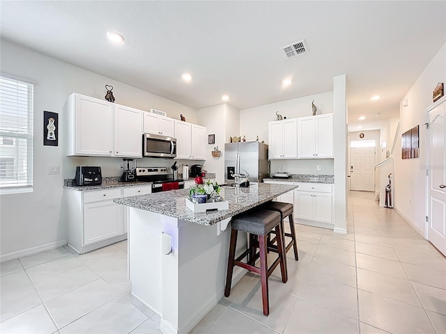 1042 Lido Dr, Howey In The Hills, FL 34737 - kitchen featuring stainless steel appliances, a sink, a breakfast bar, an island with sink, and light stone counters