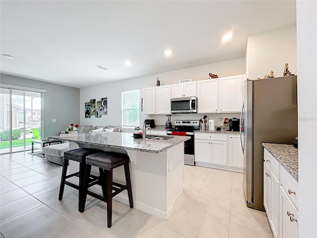 1042 Lido Dr, Howey In The Hills, FL 34737 - kitchen with stainless steel appliances, a sink, a kitchen bar, light stone countertops, and healthy amount of natural light