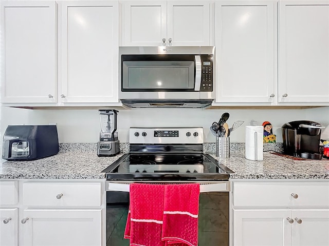 1042 Lido Dr, Howey In The Hills, FL 34737 - kitchen featuring stainless steel appliances, white cabinetry, and light stone countertops