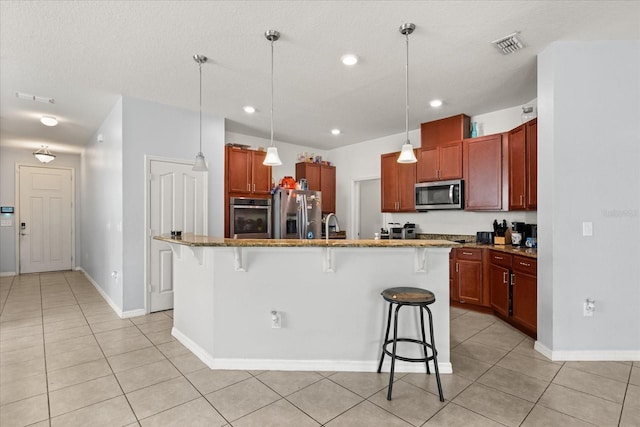 4869 Grassendale Ter, Sanford, FL 32771 - kitchen featuring stainless steel appliances, a kitchen bar, light tile patterned floors, dark stone countertops, and hanging light fixtures