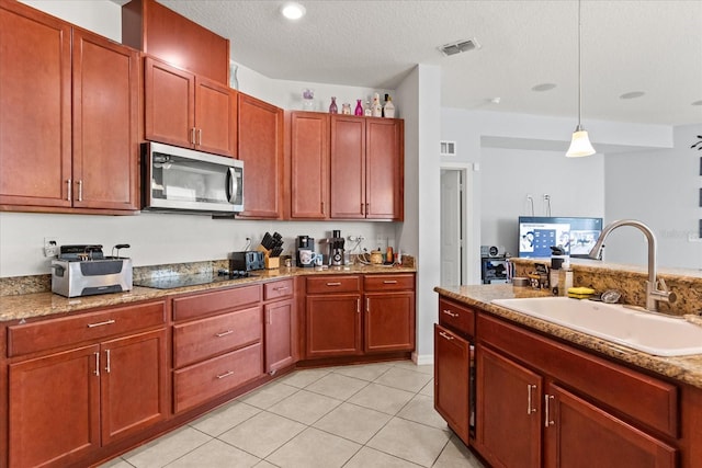 4869 Grassendale Ter, Sanford, FL 32771 - kitchen with stainless steel microwave, a sink, black electric stovetop, hanging light fixtures, and a textured ceiling