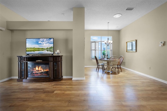 815 Cortez Ave, The Villages, FL 32159 - dining area with wood finished floors, a textured ceiling, a chandelier, and a glass covered fireplace