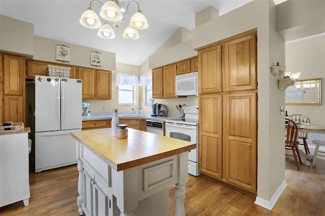 815 Cortez Ave, The Villages, FL 32159 - kitchen with white appliances, a chandelier, light countertops, vaulted ceiling, and wood finished floors