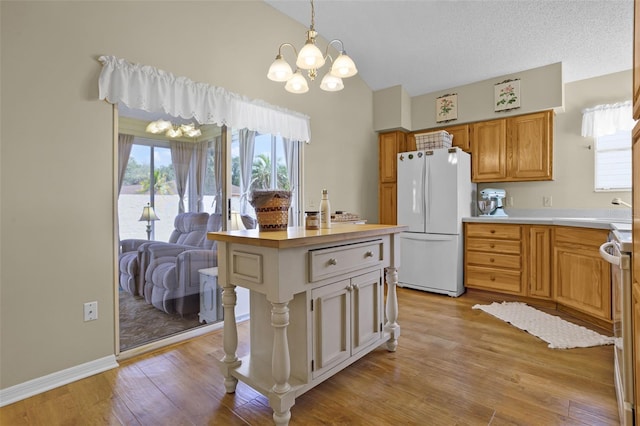 815 Cortez Ave, The Villages, FL 32159 - kitchen with freestanding refrigerator, a chandelier, light wood-style floors, hanging light fixtures, and high vaulted ceiling