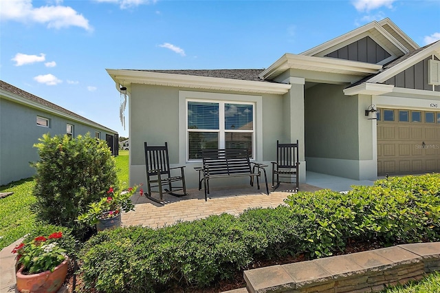 6243 Danielson Loop, The Villages, FL 32163 - property entrance featuring board and batten siding, a garage, stucco siding, covered porch, and a shingled roof