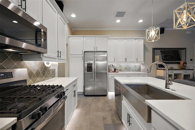 6243 Danielson Loop, The Villages, FL 32163 - kitchen with appliances with stainless steel finishes, a sink, decorative backsplash, ornamental molding, and hanging light fixtures