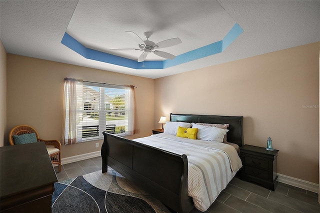 6243 Danielson Loop, The Villages, FL 32163 - bedroom with dark tile patterned floors, a raised ceiling, baseboards, a textured ceiling, and a ceiling fan