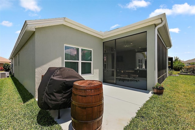 6243 Danielson Loop, The Villages, FL 32163 - rear view of property with a sunroom, a lawn, stucco siding, a patio area, and central AC unit