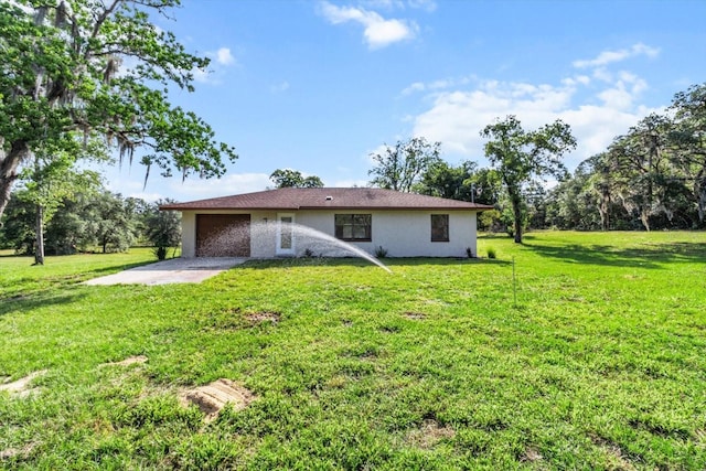 10655 N Party Ave, Dunnellon, FL 34433 - rear view of house with an attached garage, a lawn, stucco siding, and driveway