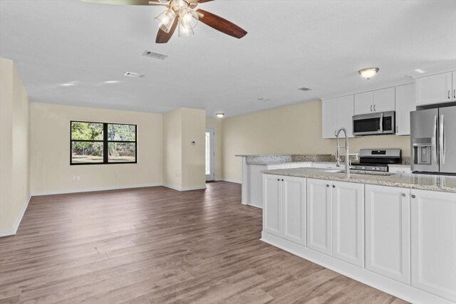 10655 N Party Ave, Dunnellon, FL 34433 - kitchen with stainless steel appliances, ceiling fan, light wood finished floors, white cabinetry, and a sink