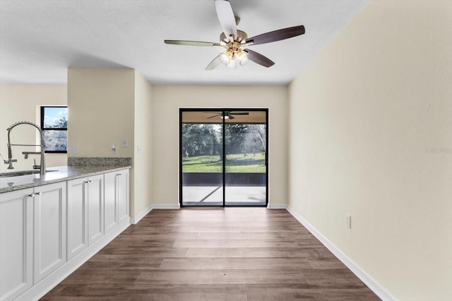 10655 N Party Ave, Dunnellon, FL 34433 - unfurnished dining area featuring a sink, dark wood-style flooring, ceiling fan, and baseboards