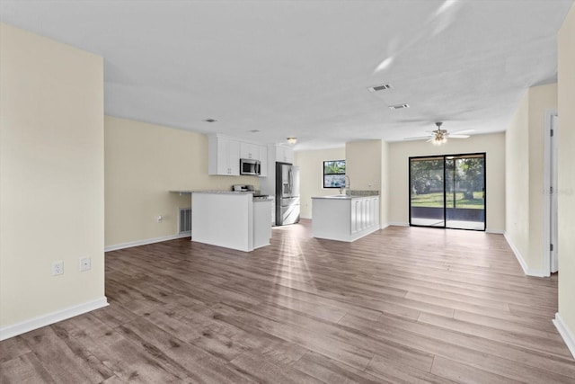 10655 N Party Ave, Dunnellon, FL 34433 - unfurnished living room featuring light wood-style floors, baseboards, ceiling fan, and a sink