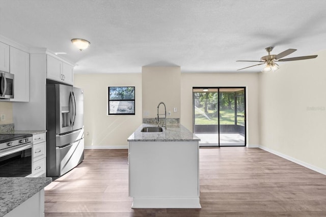 10655 N Party Ave, Dunnellon, FL 34433 - kitchen featuring appliances with stainless steel finishes, a sink, baseboards, light wood-style floors, and white cabinetry