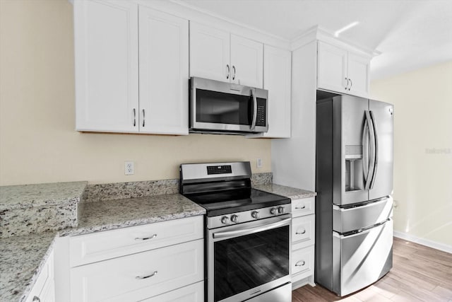 10655 N Party Ave, Dunnellon, FL 34433 - kitchen featuring appliances with stainless steel finishes, white cabinets, light wood-type flooring, light stone counters, and baseboards