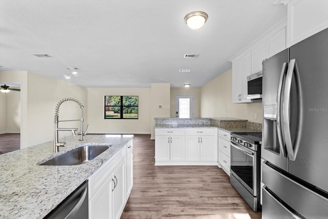10655 N Party Ave, Dunnellon, FL 34433 - kitchen with stainless steel appliances, a sink, a peninsula, white cabinetry, and light wood finished floors