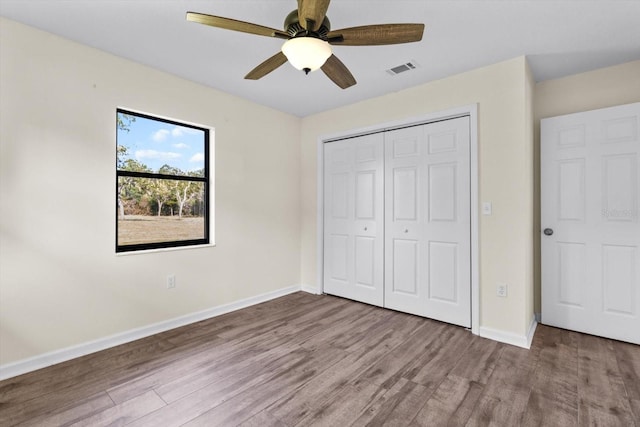 10655 N Party Ave, Dunnellon, FL 34433 - unfurnished bedroom with wood finished floors, baseboards, a closet, and ceiling fan