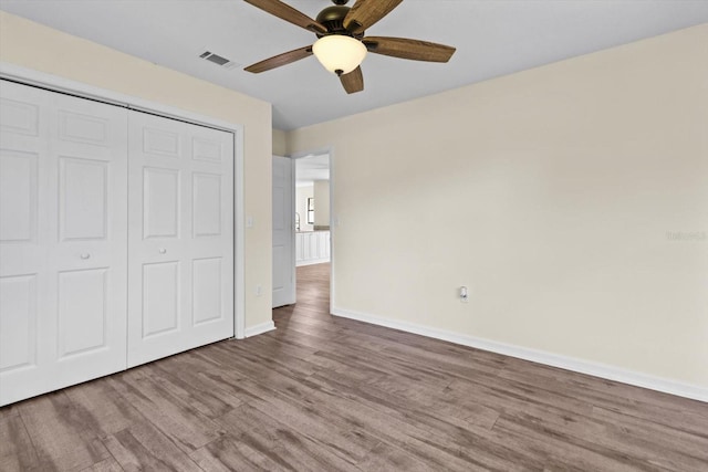 10655 N Party Ave, Dunnellon, FL 34433 - unfurnished bedroom with wood finished floors, baseboards, a closet, and a ceiling fan
