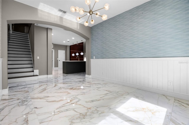 spare room with wainscoting, stairway, marble tiled floors, a chandelier, and a sink