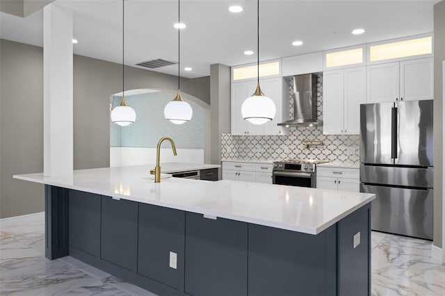 kitchen featuring appliances with stainless steel finishes, wall chimney exhaust hood, a sink, light marble finish flooring, and tasteful backsplash