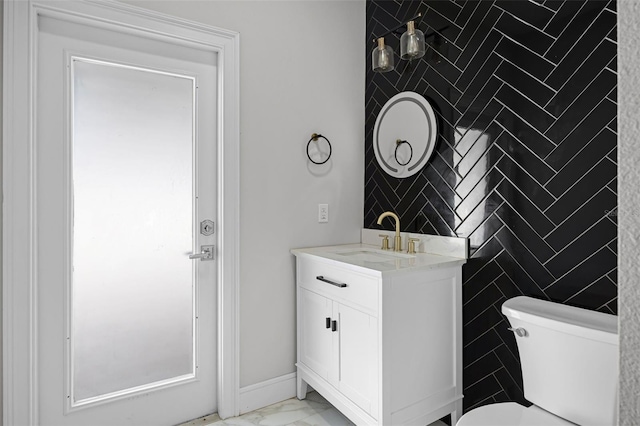 bathroom with marble look tile flooring, toilet, vanity, and tile walls