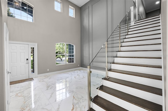 entrance foyer featuring marble tiled floors, stairway, healthy amount of natural light, a high ceiling, and baseboards