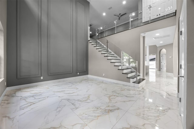 entrance foyer featuring arched walkways, marble tiled flooring, stairway, baseboards, and recessed lighting