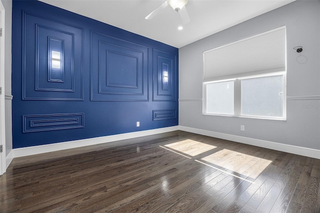 empty room featuring a ceiling fan, dark wood-style floors, and baseboards