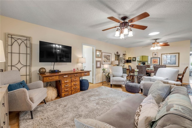 living room featuring a ceiling fan, light wood-style floors, and a textured ceiling