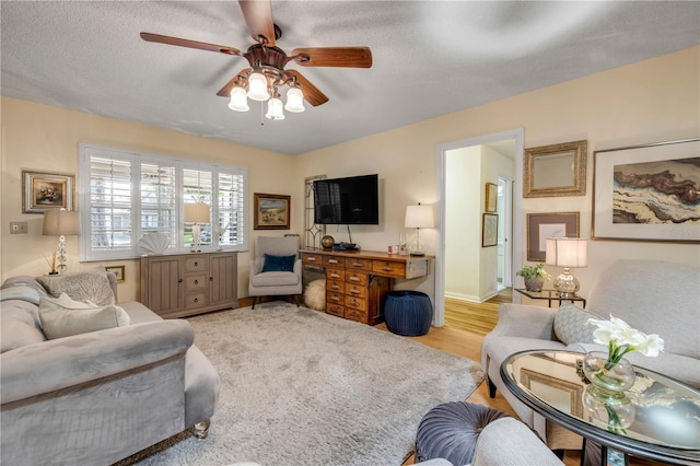 living area with ceiling fan, light wood-style flooring, and baseboards