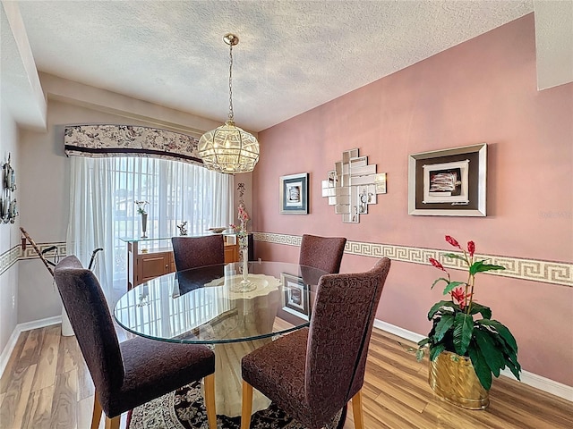 2415 Twickingham Ct, Clermont, FL 34711 - dining space featuring a chandelier, baseboards, wood finished floors, and a textured ceiling