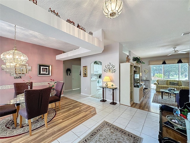 2415 Twickingham Ct, Clermont, FL 34711 - dining room with a textured ceiling, light tile patterned floors, a chandelier, a ceiling fan, and baseboards